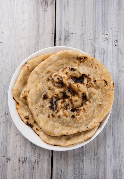 Pan plano especial indio también conocido como mantequilla tandoori roti o naan, servido en un cuarto de plato de cerámica blanca