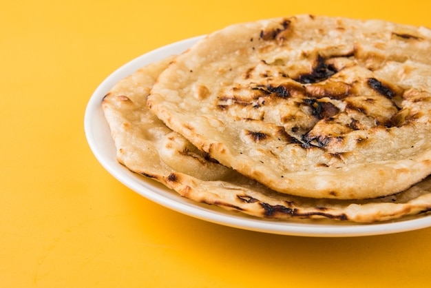 Pan plano especial indio también conocido como mantequilla tandoori roti o naan, servido en un cuarto de plato de cerámica blanca