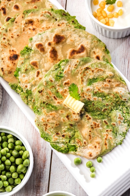 El pan plano relleno de guisantes verdes o Matar ka Paratha es una comida tradicional del norte de la India. servido con pepinillo de mango, sobre fondo cambiante, enfoque selectivo