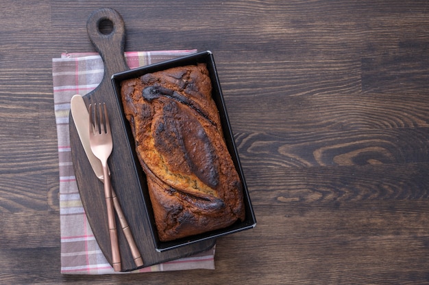 Pan de plátano casero con canela sobre un fondo de madera, de cerca, vista superior. Hogaza de pan de plátano, recién horneado del horno en el fondo de la tabla de madera, estilo rústico vintage bodegón. Concepto de panadería