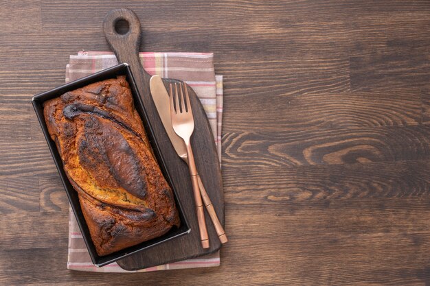 Pan de plátano casero con canela sobre un fondo de madera, de cerca, vista superior. Hogaza de pan de plátano, recién horneado del horno en el fondo de la tabla de madera, estilo rústico vintage bodegón. Concepto de panadería