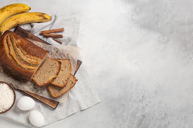 Pan de plátano fresco en rodajas con ingredientes sobre fondo claro