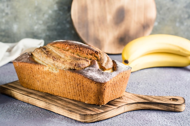 Pan de plátano en una tabla de cortar y fruta fresca en la mesa Moda en las redes sociales