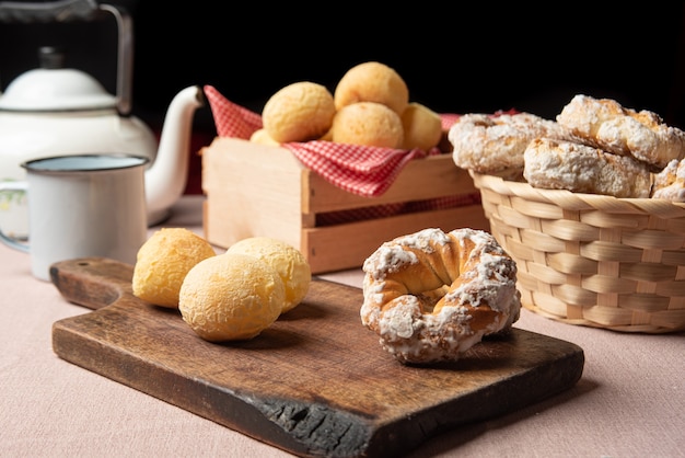 Pan de queso de Brasil y galleta dulce y una taza de café sobre una mesa con mantel beige, enfoque selectivo.