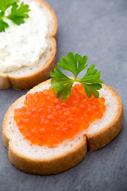 Pan con queso crema fresco y caviar rojo en mesa