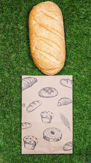Pan recién horneado y bolsa de papel arrugada en un fondo de hierba Vista superior