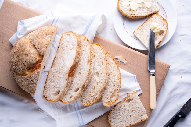 Pan recién horneado casero y pan de molde en rústica mesa de madera blanca.