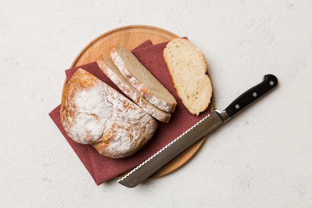 Pan recién horneado cortado con cuchillo en una tabla de madera vista superior Pan rebanado y cuchillo