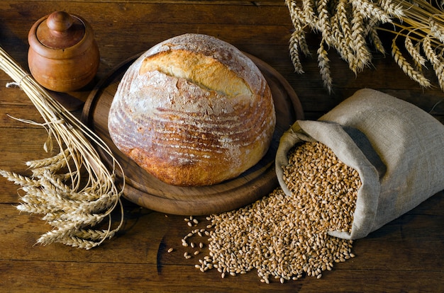 Pan recién horneado, espiguillas y grano de trigo en la mesa de madera. Estilo rústico. Vista superior.