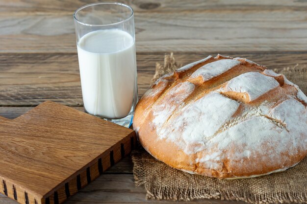 Pan recién horneado en la mesa de la cocina de madera gris con un vaso de leche, repostería casera.