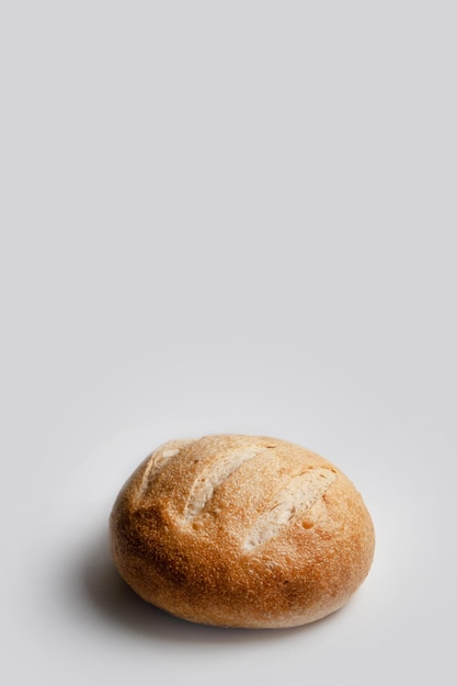 Pan redondo de pan de trigo sobre masa fermentada sobre un marco vertical de fondo claro con espacio para texto