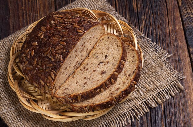 Pan con semillas y rodajas de frutos secos sobre la mesa de madera antigua