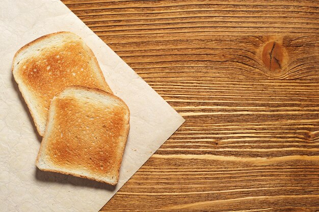 Pan tostado asado sobre fondo de madera, vista superior