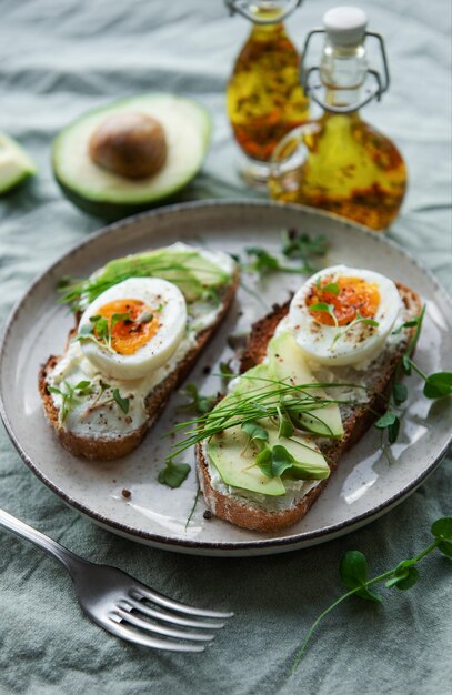 Pan tostado huevos cocidos rebanada de aguacate microgreens en un plato