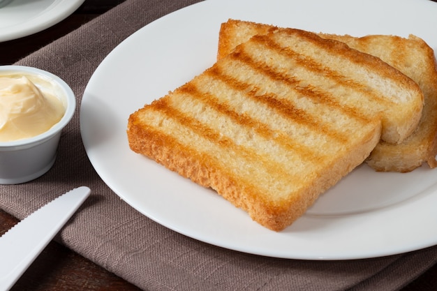 Pan tostado con mantequilla en un plato blanco.