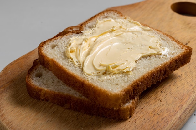 Pan tostado con margarina en una madera sobre la mesa