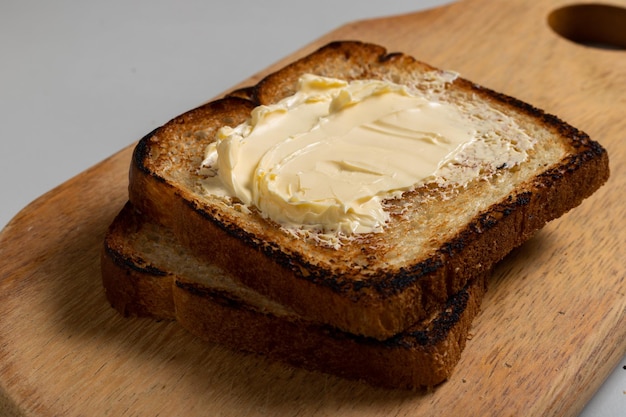 Pan tostado con margarina en una madera sobre la mesa