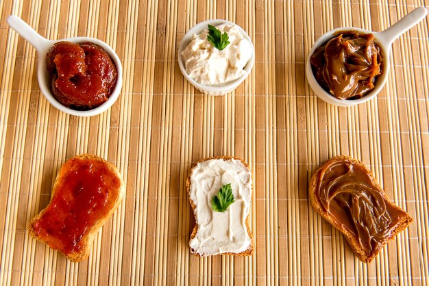 Pan tostado con mermelada, dulce de leche y crema de ricotta en una mesa de desayuno.