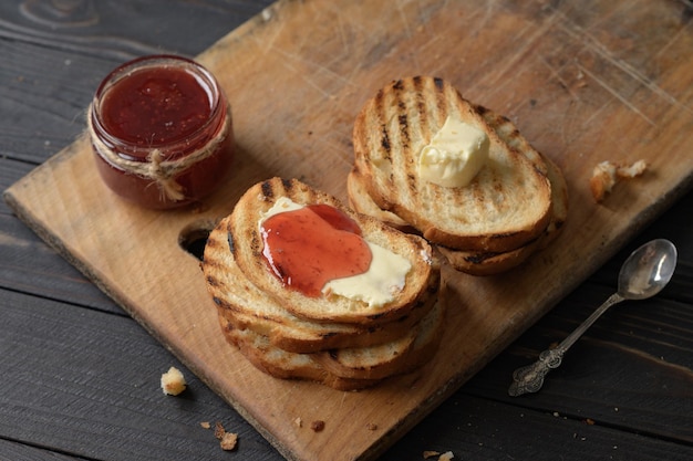 Pan tostado con mermelada de fresa casera y sobre mesa rústica con mantequilla para el desayuno o brunch