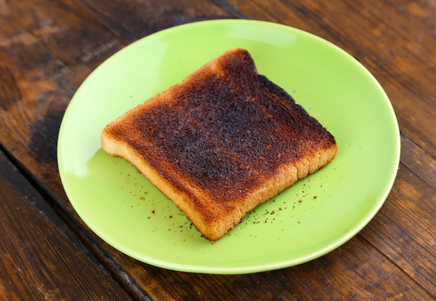 Pan tostado quemado en un plato verde claro sobre fondo de mesa de madera