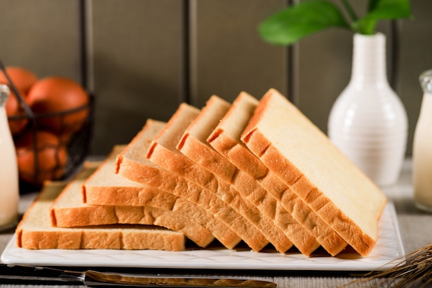 Pan tostado en rodajas de pan blanco (Shokupan o Roti Tawar) para el desayuno sobre fondo de madera, servido con huevo y leche. Imagen del concepto de panadería