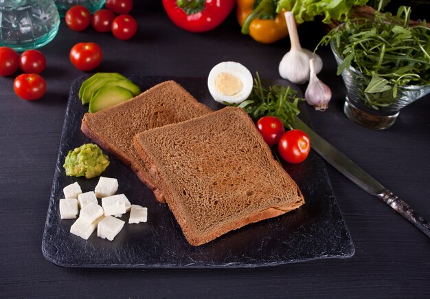 Pan tostado en rodajas en un plato negro con verduras