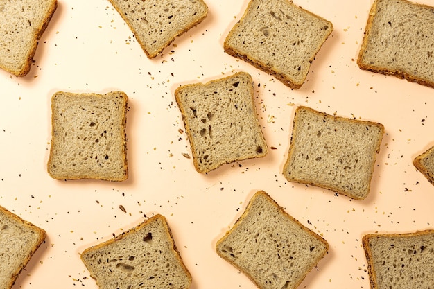 Pan tostado de trigo en rodajas con cereales aislado sobre fondo de colores.