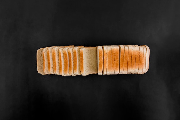 Pan tostado de trigo en rodajas sobre un fondo negro Flay lay