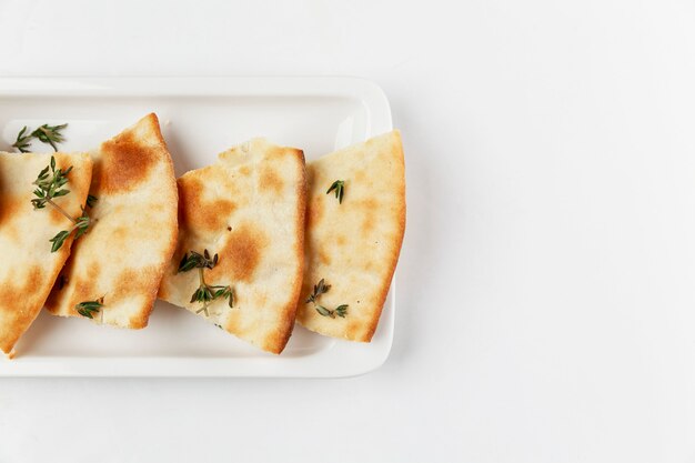 Pan tradicional italiano con romero. Apetitosas rebanadas en un plato blanco. Fondo blanco. Espacio para texto. De cerca.