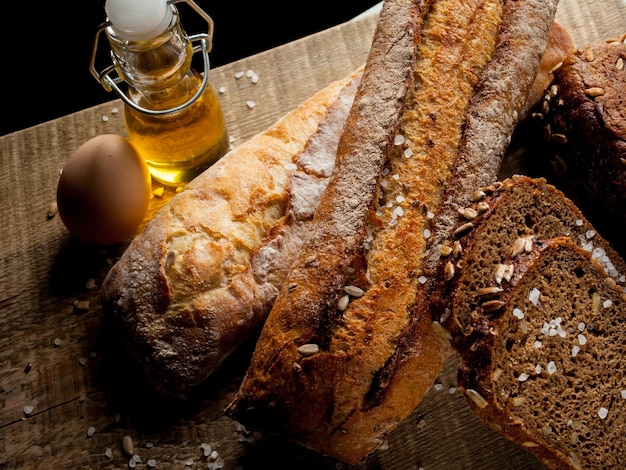 Pan tradicional recién horneado con huevo y aceite de girasol sobre una mesa de madera baguette con sal