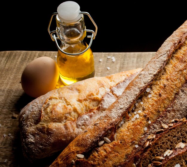 Pan tradicional recién horneado con huevo y aceite de girasol sobre una mesa de madera baguette con sal