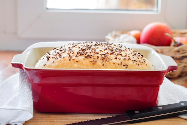 Pan de trigo casero con semillas de lino en una fuente para horno de cerámica