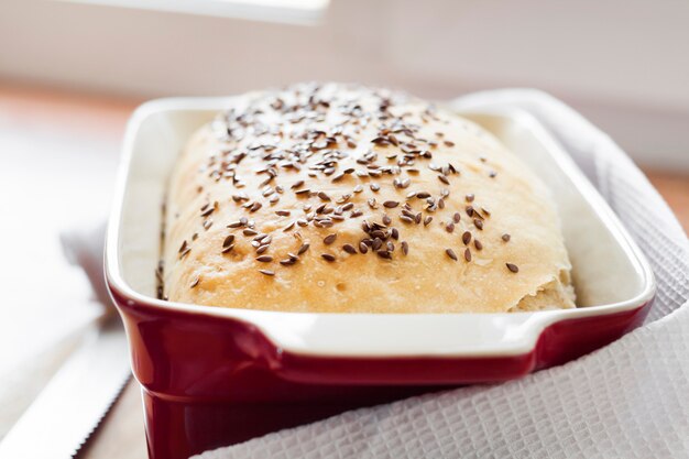 Pan de trigo casero con semillas de lino en una fuente para horno de cerámica