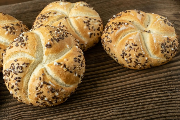 Pan de trigo integral sobre fondo de madera Montón de rollos kaiser con sésamo