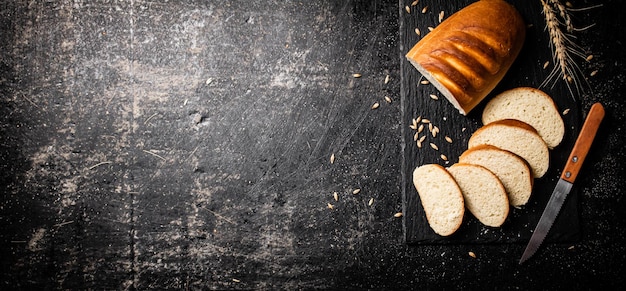 Foto pan de trigo rebanado con un cuchillo en una tabla de piedra