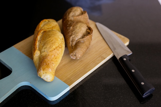 Pan turco fresco y cuchillo sobre tabla para cortar madera