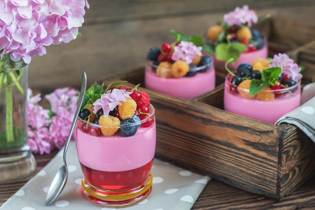 Panacotta deliciosa de bayas de verano multivitamínicas Comida dulce con frambuesas arándanos grosellas picatostes y ramo de hortensias rosa menta fondo de madera oscura