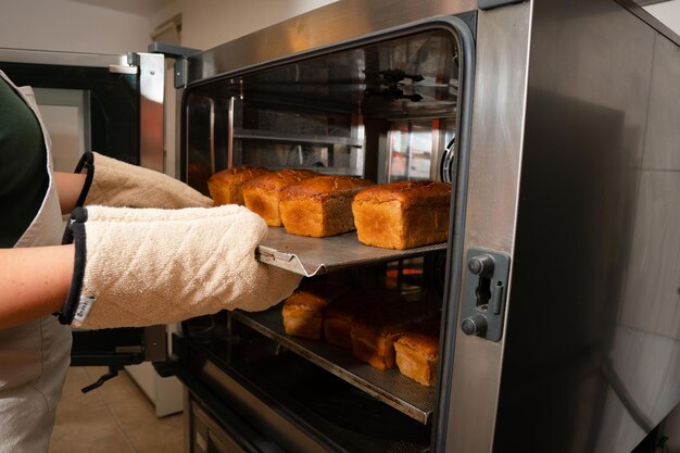 Foto una panadera con guantes térmicos saca pan de centeno recién horneado del horno