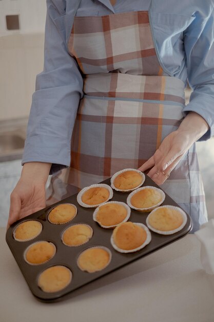 Una panadera sostiene pasteles recién horneados mostrando sus pasteles caseros