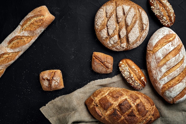 Panadería dorada rústica hogazas de pan y bollos sobre fondo de pizarra negra