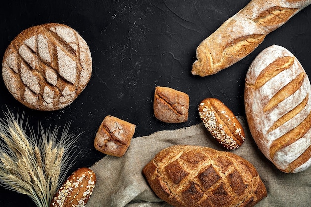 Panadería dorada rústica hogazas de pan y bollos sobre fondo de pizarra negra