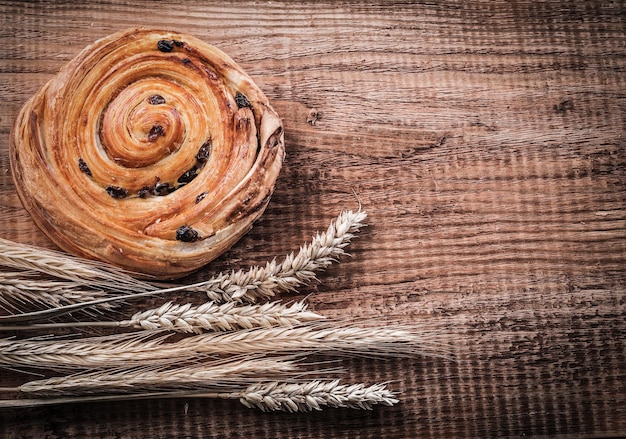 Panadería rica con pasas de espigas de trigo en concepto de comida y bebida de tablero de madera de roble