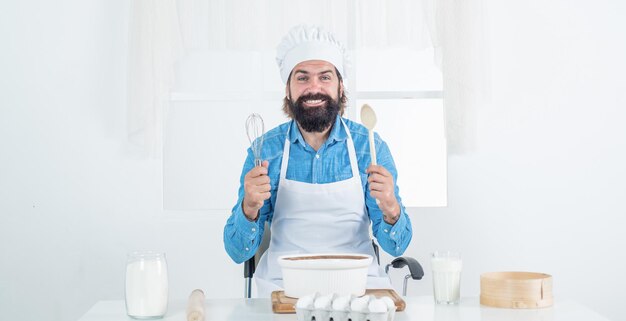 Panadero confiado. hombre barbudo maduro usa sombrero de chef. cocinero masculino preparando comida en la cocina de casa. hipster brutal en delantal cocinando comida. hora de comer. horneado feliz. concepto de limpieza.