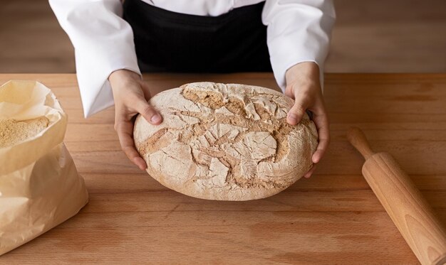 Panadero de cultivos sosteniendo pan sobre la mesa