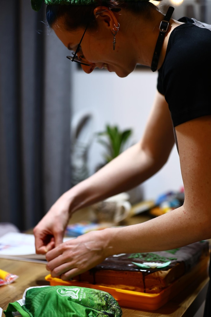 Foto un panadero decorando meticulosamente un pastel de cumpleaños con glaseado y precisión