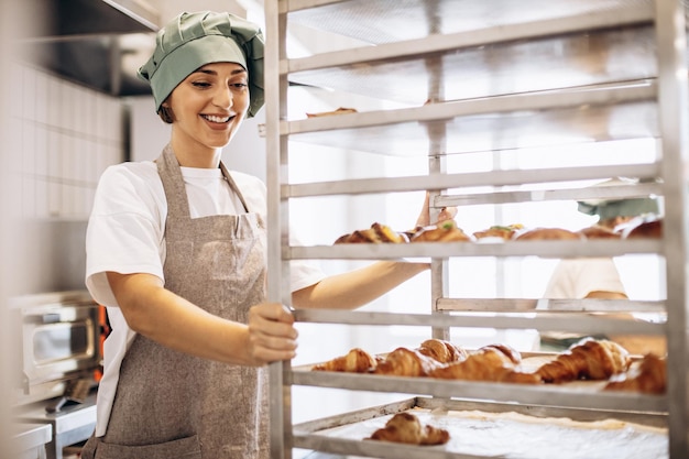 Panadero femenino en la cocina con croissants