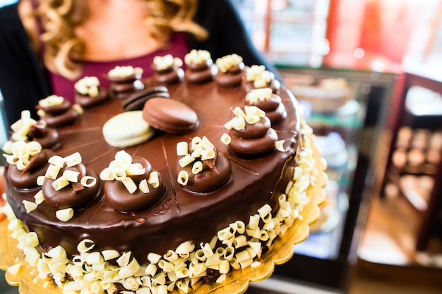 Panadero femenino que presenta la torta en confitería