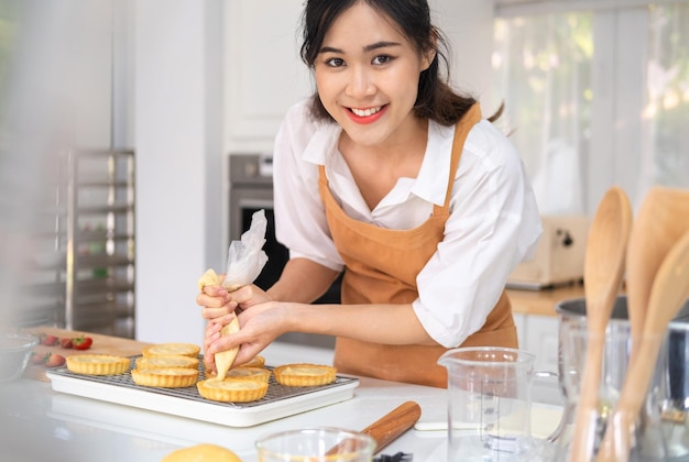 Panadero femenino usando manga pastelera para decorar tarta de frutas con concepto de estilo de vida interior de queso crema