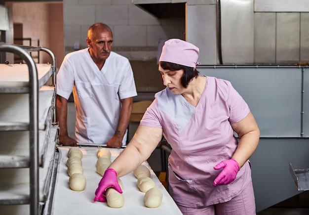 El panadero forma la masa para hornear pan y la pone en la bandeja del horno en la fabricación