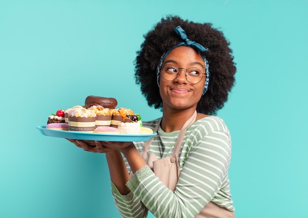 Panadero joven bonita mujer afro con tortas